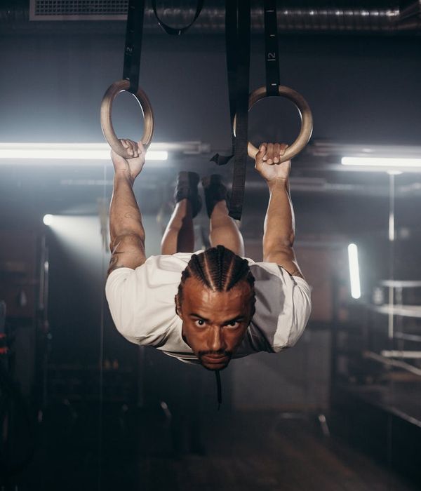 A man performing a focused strength exercise in a dark gym environment.